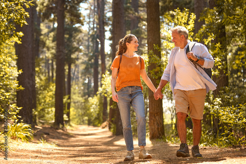 Senior Retired Couple Holding Hands Hiking Along Trail In Countryside