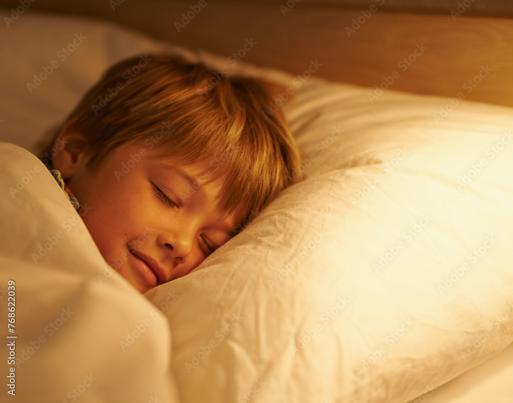 Boy, pillow and rest for night, sleeping and tired with fatigue and peace. Child, dreaming and exhausted with blanket, bed and bedroom with lamp for serene childhood at home or house for childcare Boy, pillow and rest for night, sleeping and tired with fatigue and peace. Child, dreaming and exhausted with blanket, bed and bedroom with lamp for serene childhood at home or house for childcare