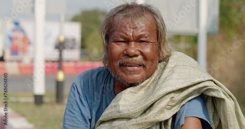 A smiling Asian man who is a poor ragpicker or collects garbage and sells, sitting on the side of the road in the morning photo