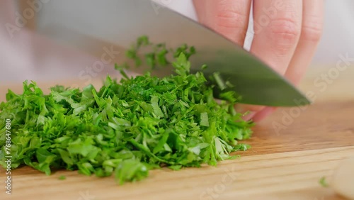 Macro, chef cuts greens, kale, parsley, cilantro with a sharp knife on a wooden board. Healthy eating, home cooking, diet, diet food, vegetarian food. Close-up, front view