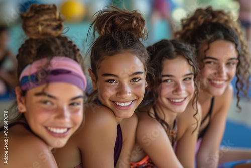 Four teenage girls in sportswear, beaming with joy during a gymnastics class