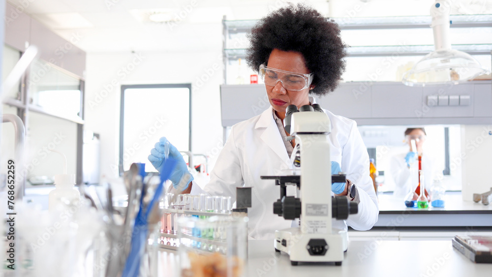African American female scientist working at the lab and examining some samples on the microscope African American female scientist working at the lab and examining some samples on the microscope