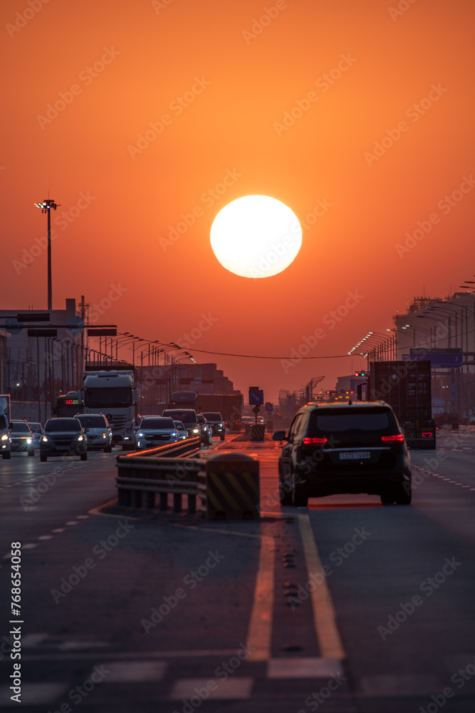 A road with cars passing by with a sunset view

