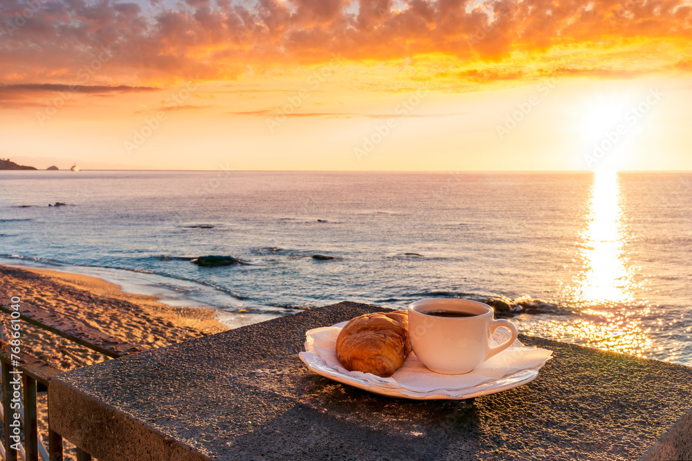 concept of street outdoor breakfast with a cup of tea or coffee on a morning coast during sunrise. landscape of city embarkment with sea water and cloudy sky on background