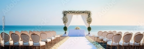 A beach wedding with a white arch and chairs. The chairs are arranged in a row and the arch is decorated with flowers. The beach is calm and the water is blue