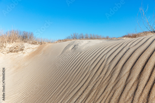 Sand dune against the blue sky. Beautiful coastal landscape.