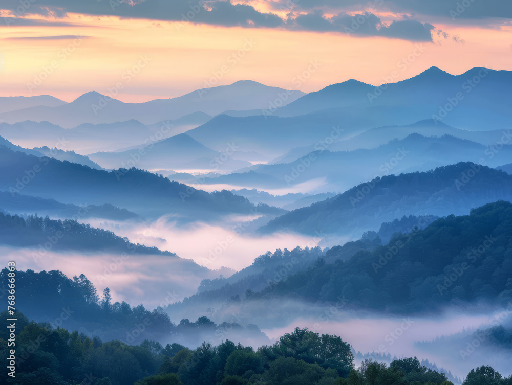 Multi-layered mountain ranges bathed in the soft light of sunrise peering through rolling fog