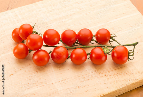 Bunch of red tomatoes on a wooden board.