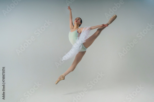 young Japanese ballerina in a photo studio does a grand jete splits in a jump