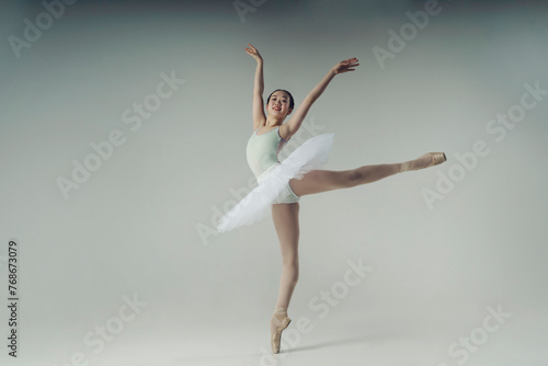 young Japanese ballerina in a photo studio makes an arabesque showing balance and plasticity