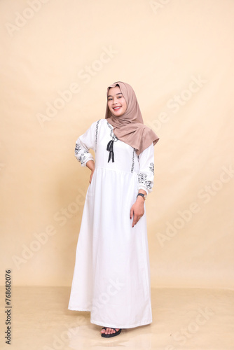 Full body portrait of a beautiful young Asian Muslim woman in a hijab posing cheerfully holding her waist and dress. for advertising, content, banners and Ramadan