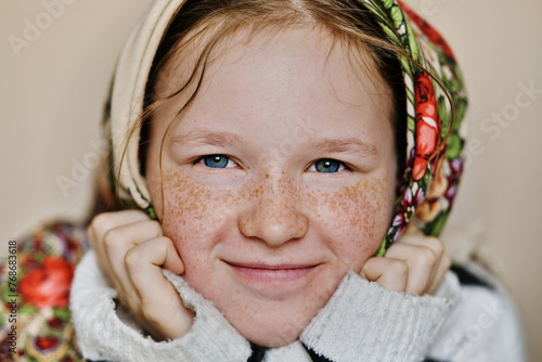 Portrait of charming young girl with a lot of freckles in traditional headscarf. Close-up portrait of smiling girl. photo
