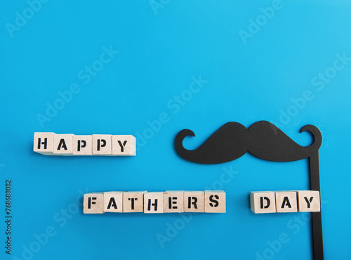 Inscription Happy Father's Day and black mustache decor on blue background