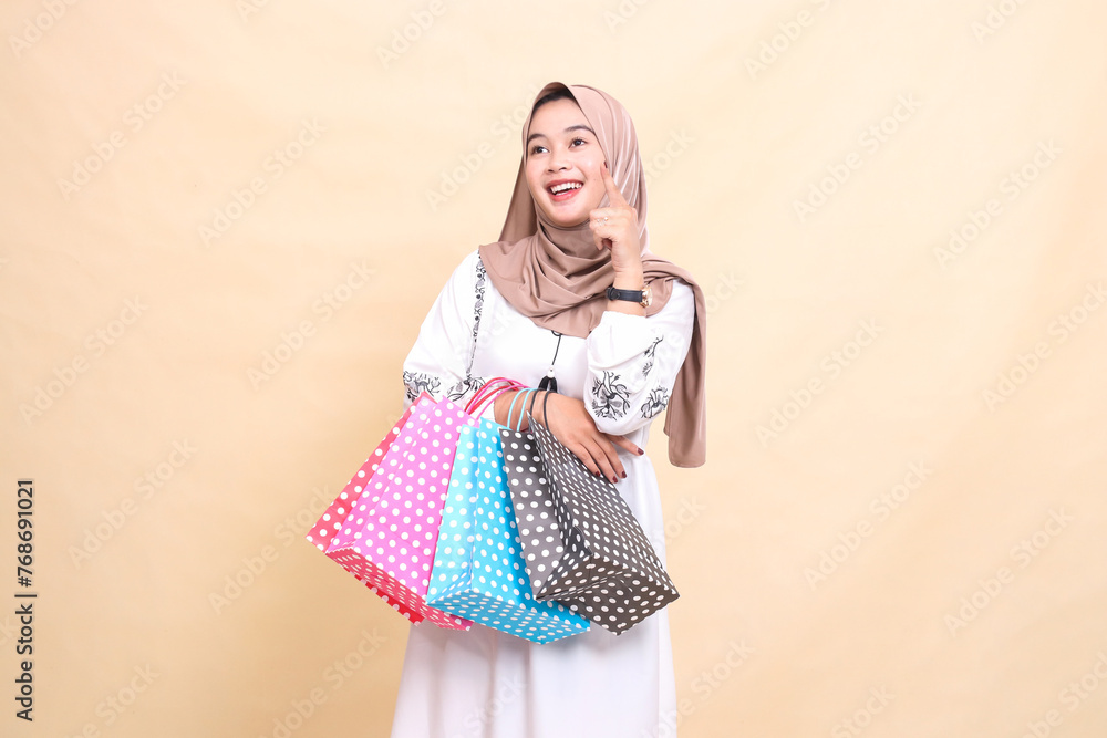 The story of a young Asian Muslim woman wearing a hijab got the idea of looking up and carrying shopping bags. for advertising, culture, Eid and Ramadan The story of a young Asian Muslim woman wearing a hijab got the idea of looking up and carrying shopping bags. for advertising, culture, Eid and Ramadan