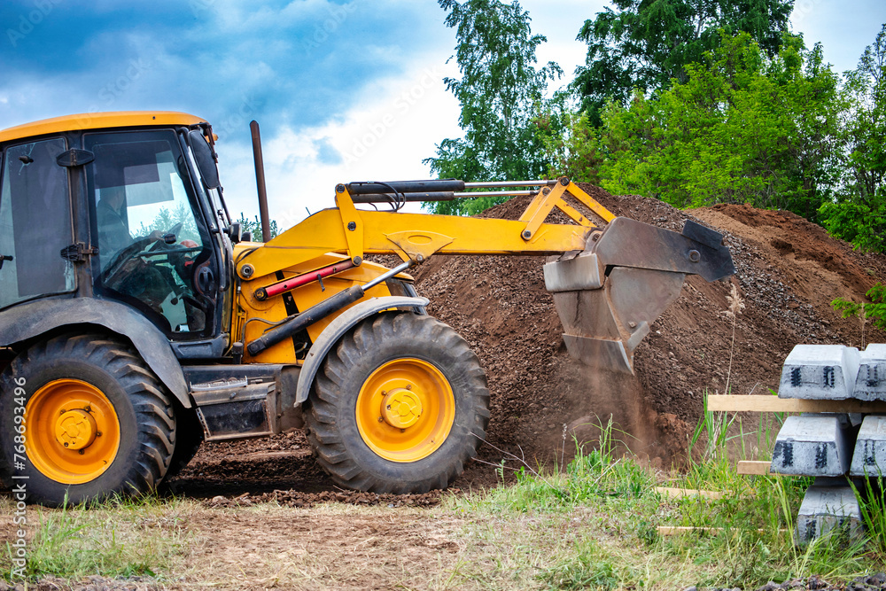A bulldozer or a loader is actively digging into a large pile of dirt, moving the earth to clear or level the area