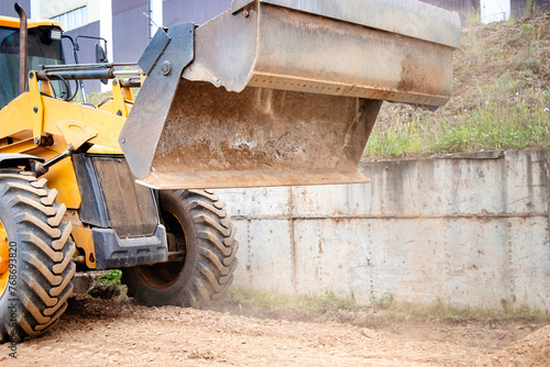 A yellow bulldozer or a loader is parked in front of a building, ready for construction work