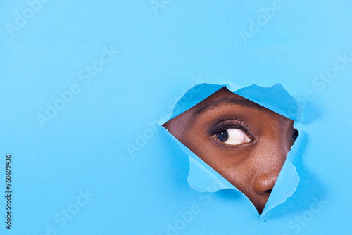 Tear, hole and eye of person on blue background for vision, eyesight and looking for inspiration. Mockup space, creative aesthetic and isolated eyes in studio for curiosity, wondering or perception © peopleimages.com