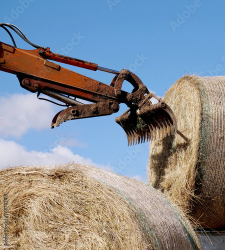 Mechanical arm with rake on hay bale