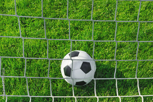 textured soccer game field with close-up ball in front of the soccer goal - soccer ball in soccer net. © Igor Link