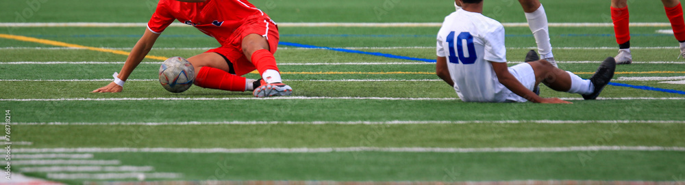 Soccer players falling while chasing a soccer ball Soccer players falling while chasing a soccer ball