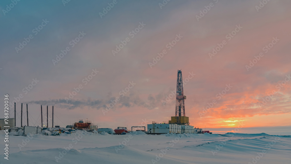 Drilling wells in an Arctic oil and gas field. Polar day sunrise in the background. Winter northern landscape against the beautiful sky Drilling wells in an Arctic oil and gas field. Polar day sunrise in the background. Winter northern landscape against the beautiful sky