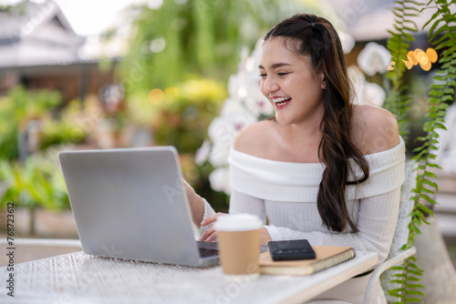 Young woman enjoying a video call using a laptop at an outdoor cafe. Enjoy chatting on laptop screen.