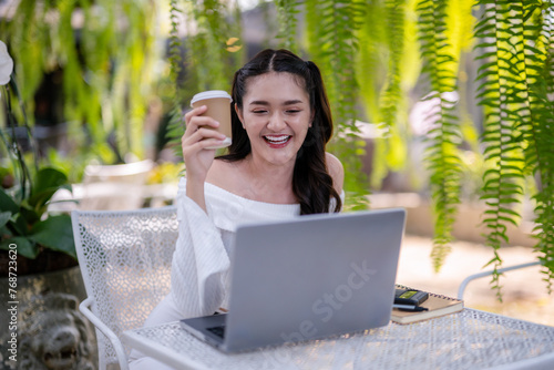 Young woman enjoying a video call using a laptop at an outdoor cafe. Enjoy chatting on laptop screen.