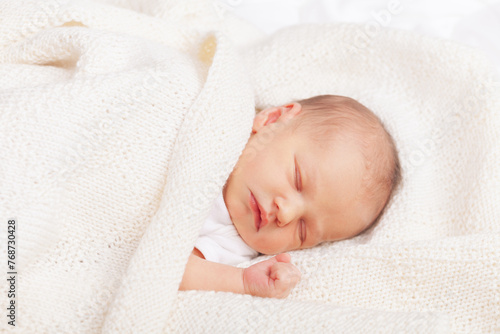 Newborn Baby Asleep Wrapped in Knit Blanket
