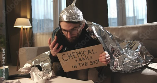 A paranoid, a supporter of pseudoscience holds a sign with a conspiracy slogan.