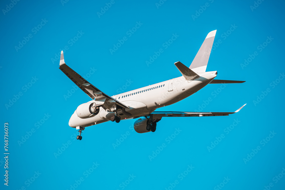 Obraz premium Rear view of a landing airplane in the blue sky.