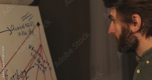 A man is standing near a crazy table on a conspiracy theory board.