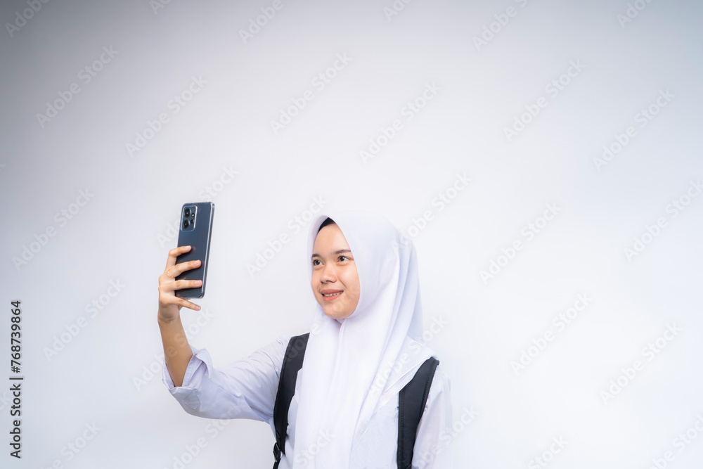 Young beautiful student woman in white and grey uniform taking selfie using mobile phone Young beautiful student woman in white and grey uniform taking selfie using mobile phone