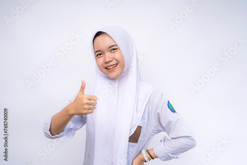 portrait of Indonesian high school student in white and grey uniform giving thumbs up at Copy Space Advertising Your Text. Education concept