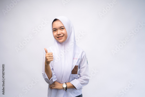 portrait of Indonesian high school student in white and grey uniform giving thumbs up at Copy Space Advertising Your Text. Education concept