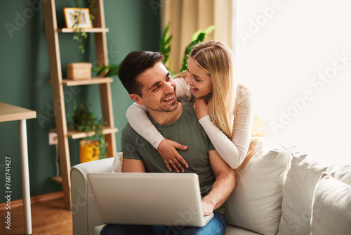Beautiful young happy couple having video call via laptop at home3