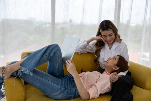 Bonding Over Entertainment: Lesbian Couple Relaxes on Sofa, Watching Content on Laptop in Cozy Living Room