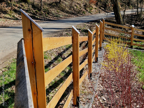 rural farm style wooden fence. the posts from the beam are on metal spikes so they don't rot from the ground. the top is beveled and covered with a sheet metal roof against water ingress photo