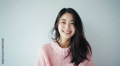 A beautiful Chinese woman, wearing a pink sweater sitting on the floor smiling at the camera photo