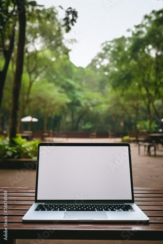 Laptop with blank screen on wooden table in coffee shop with nature background