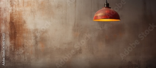 A red light fixture is suspended from the ceiling, casting a warm glow against a vintage concrete wall. The contrast between the vibrant red light and the textured wall creates a striking visual