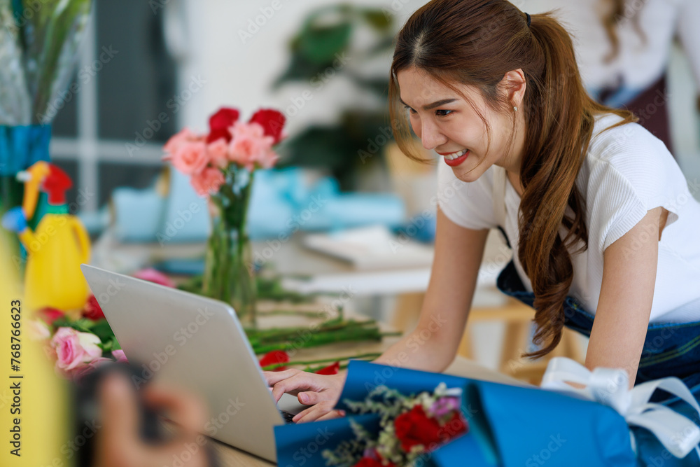 Small Business Success: Asian Woman Entrepreneur Runs Florist Shop, Utilizing Laptop for Business Management and Online Sales