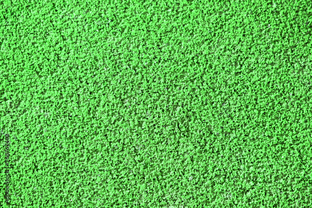 Textured green background, rubber coating for stadiums, running tracks, tennis courts. Top view, close-up Textured green background, rubber coating for stadiums, running tracks, tennis courts. Top view, close-up