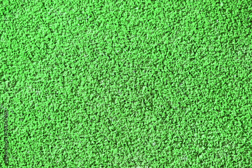 Textured green background, rubber coating for stadiums, running tracks, tennis courts. Top view, close-up