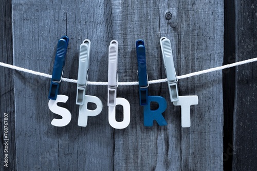 Close-up of three colorful clothespins holding the word "sport" on a clothesline.