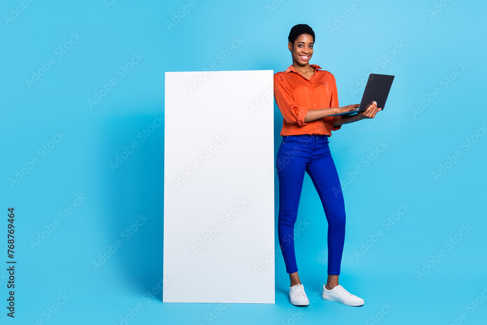 Photo of freelancer lady hold pc white vertical empty space info board placard wear brown shirt isolated blue color background Photo of freelancer lady hold pc white vertical empty space info board placard wear brown shirt isolated blue color background