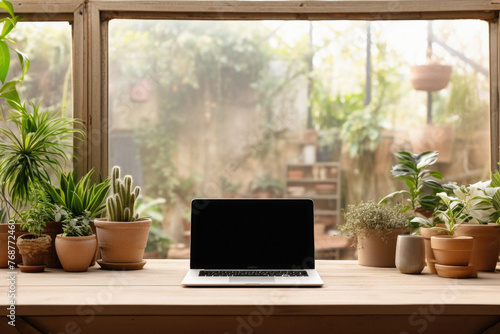 Laptop with blank screen on wooden table in front of window .