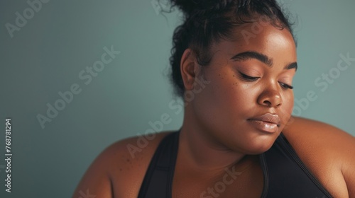 A woman with a side profile closed eyes and a serene expression wearing a black top against a soft blue background.