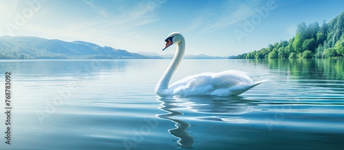 Graceful white swan glides peacefully through calm lake waters with majestic mountains in the distance © vxnaghiyev