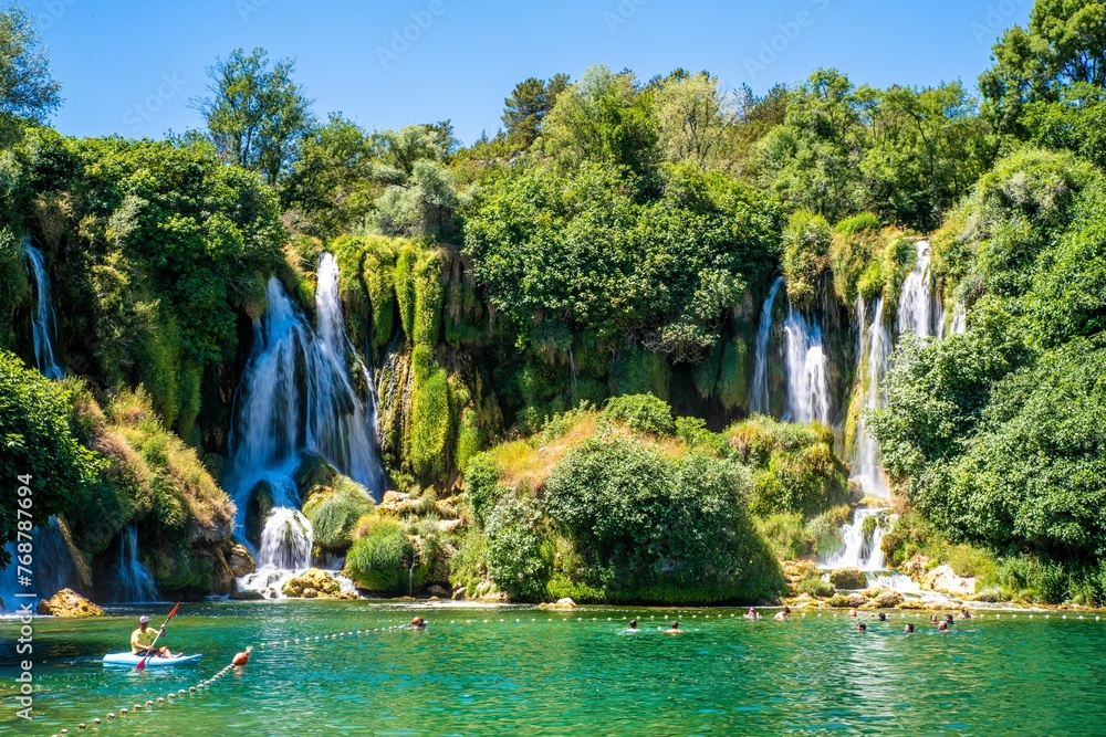 Naklejka premium Majestic Kravica Waterfall cascading down amidst lush greenery and trees in Bosnia and Herzegovina