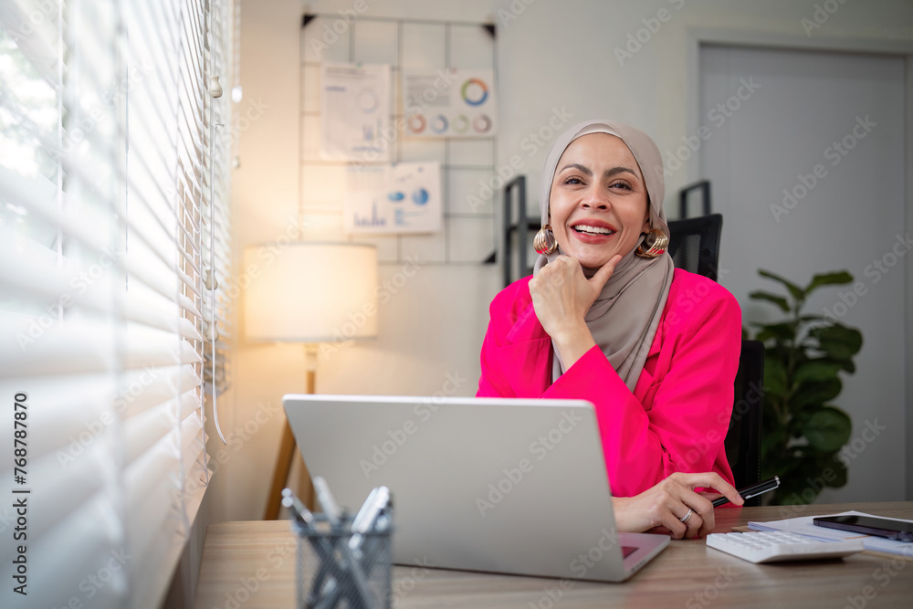 Muslim business woman hijab working about financial with business report and calculator on laptop in home office Muslim business woman hijab working about financial with business report and calculator on laptop in home office